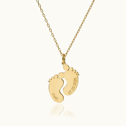 a gold necklace with a baby's footprints on it