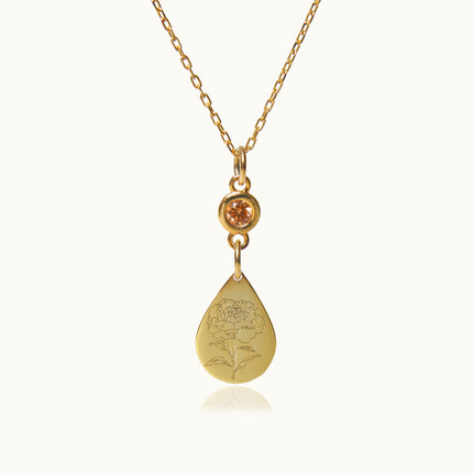 a gold necklace with an orange stone hanging from it