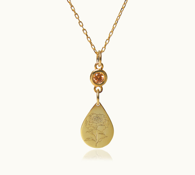 a gold necklace with an orange stone hanging from it