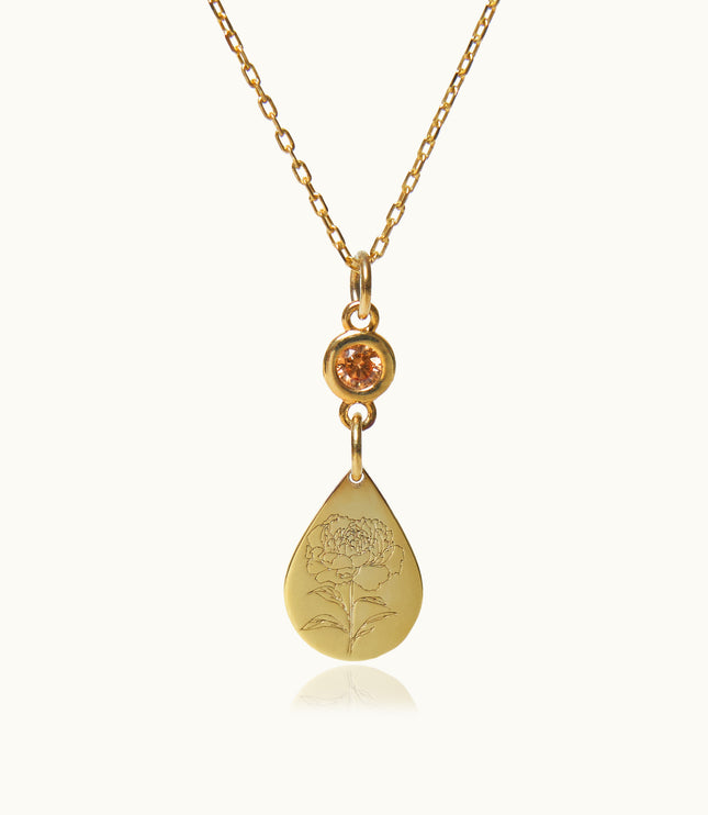 a gold necklace with an orange stone hanging from it