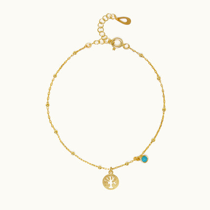 a gold bracelet with a tree charm