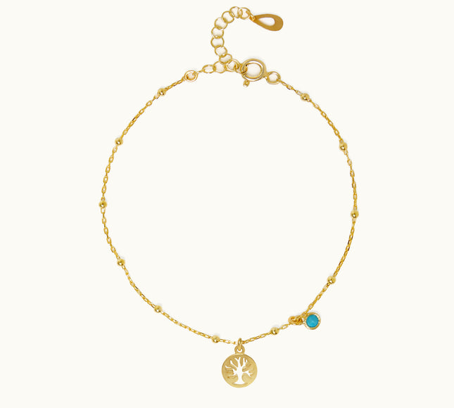 a gold bracelet with a tree charm