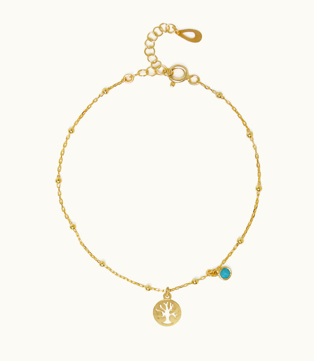 a gold bracelet with a tree charm